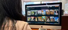 Persona frente a un computador, con varias imágenes visibles en la pantalla.